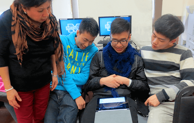 Students holding an iPad and looking at a lesson