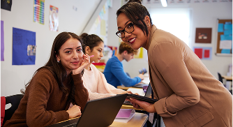 Teacher assisting students with laptop